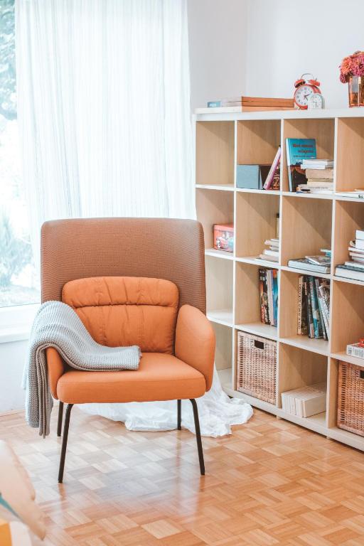 an orange chair in a room with a book shelf at Entoli Apartment in Podnanos