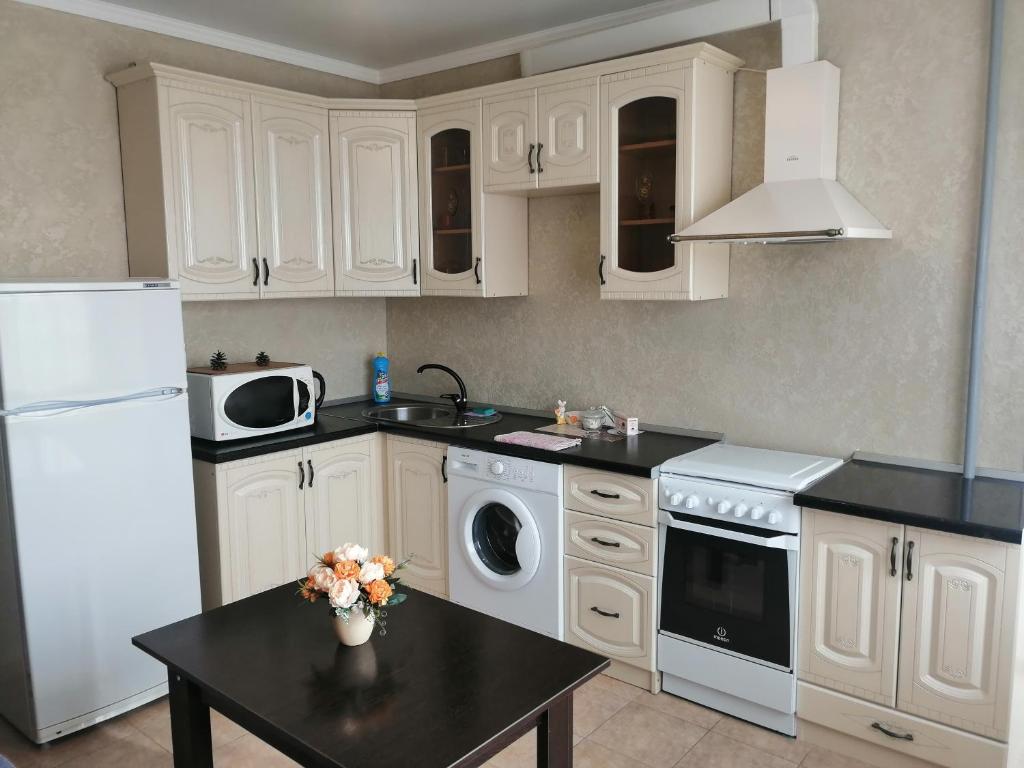 a kitchen with white appliances and a black table at Московская улица, 97 Апартаменты 5этаж in Pyatigorsk