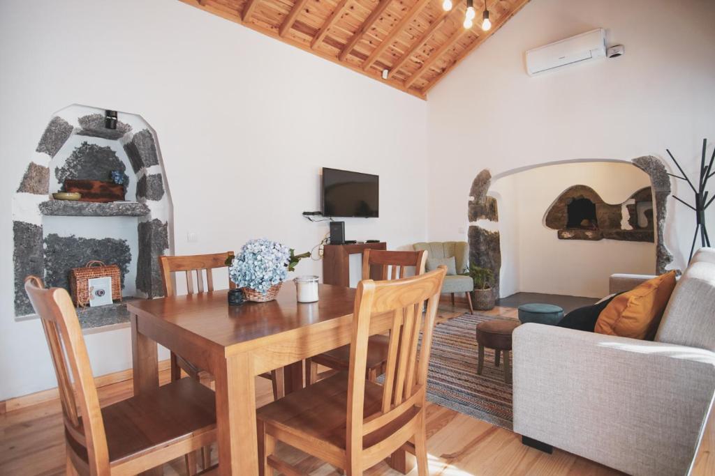 a dining room with a table and a couch at Casas da Ribeira in Santa Bárbara