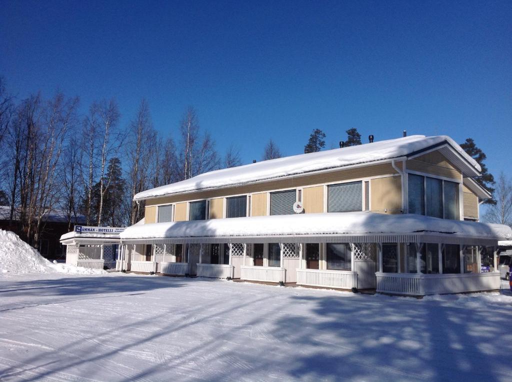 un grand bâtiment avec de la neige au sol dans l'établissement Ämmän Hotelli, à Suomussalmi