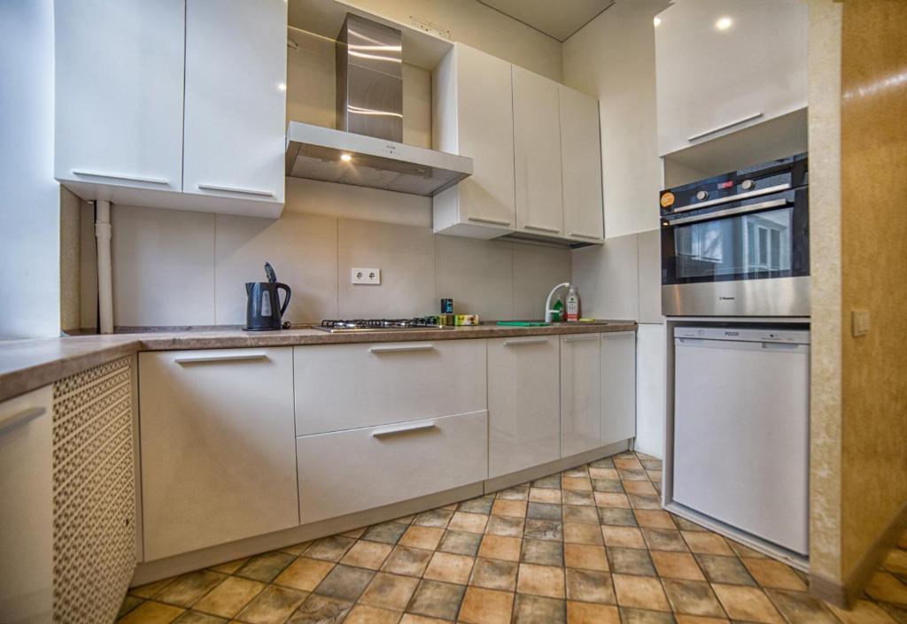 a kitchen with white cabinets and a tile floor at Apartment on Kommunisticheskaya in Smolensk