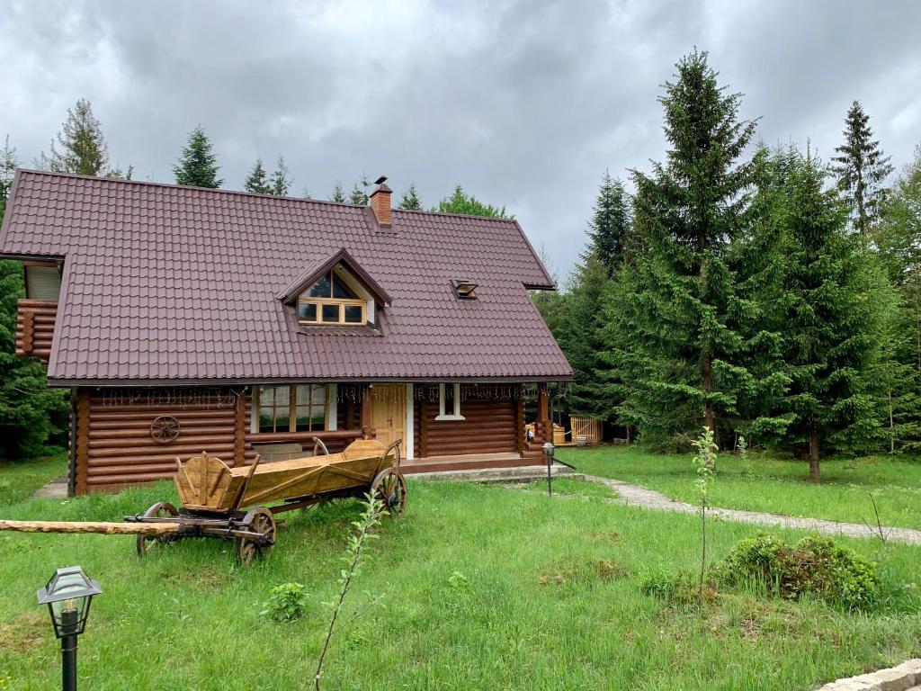 a log cabin in a field next to a house at Котедж Гута in Guta