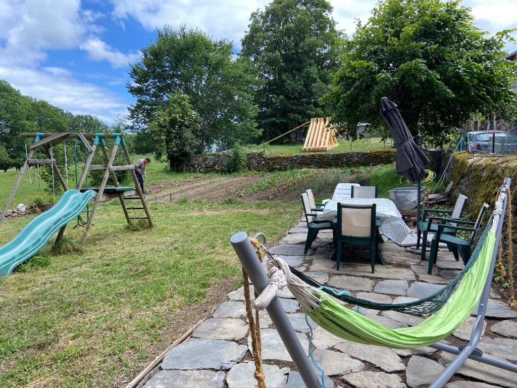 a patio with two swings and a table and a playground at Maison de famille au plateau du Mezenc in Les Vastres