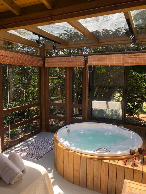 a jacuzzi tub in a room with windows at Pousada Watu Kerere in Praia do Rosa