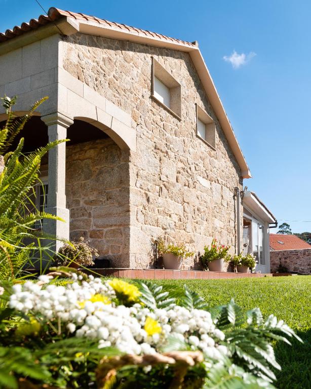 a stone building with an arch in a yard at Turismo Casa Benito in Villanueva de Arosa