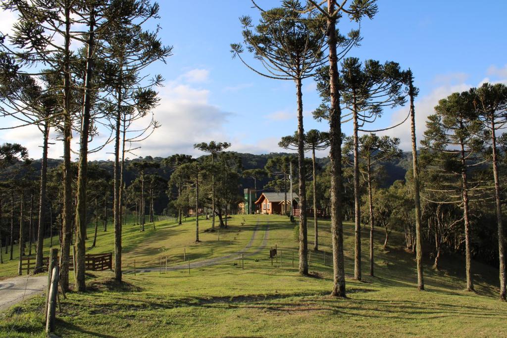 a field with trees and a house in the distance at Chalé Bienz - Hospedagem Rural in Urubici