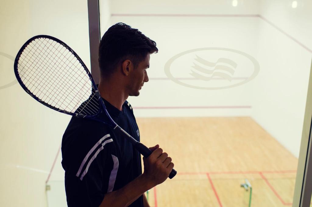 a man holding a tennis racket in a room at Crowne Plaza Yas Island by IHG in Abu Dhabi