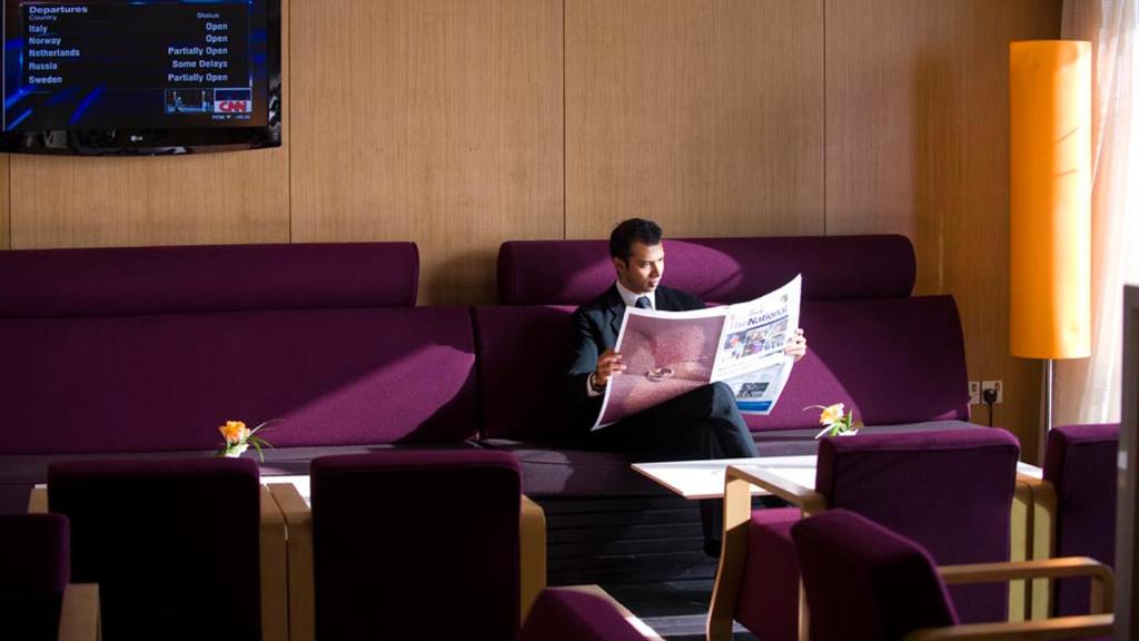 a man sitting on a couch reading a newspaper at Crowne Plaza Yas Island by IHG in Abu Dhabi