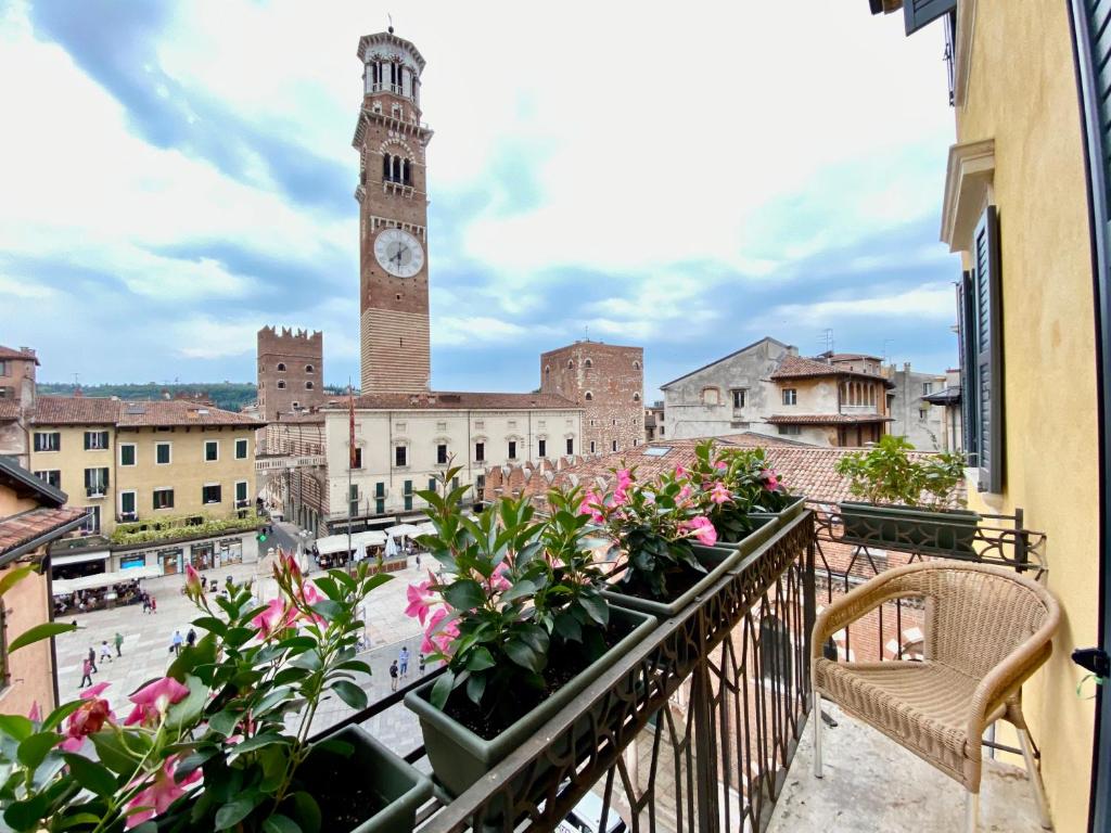 einen Balkon mit Blumen und einem Uhrturm in der Unterkunft Hotel Aurora in Verona