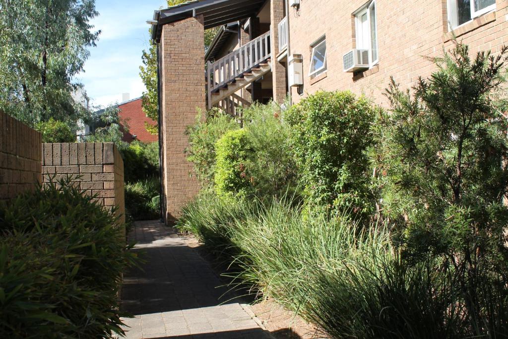 a garden in front of a brick building with bushes at Adelaide Dress Circle Apartments - Archer Street in Adelaide