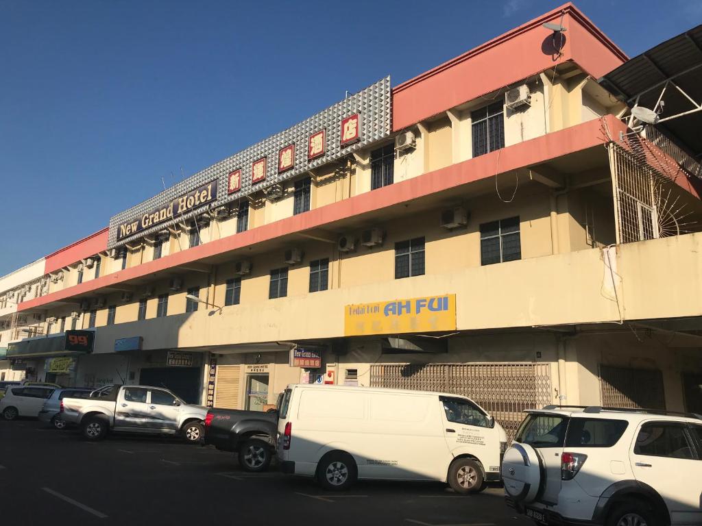 un grand bâtiment avec des voitures garées devant lui dans l'établissement New Grand Hotel, à Keningau