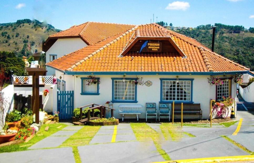 una pequeña casa blanca con techo naranja en Pousada Ararinha Azul, en Campos do Jordão