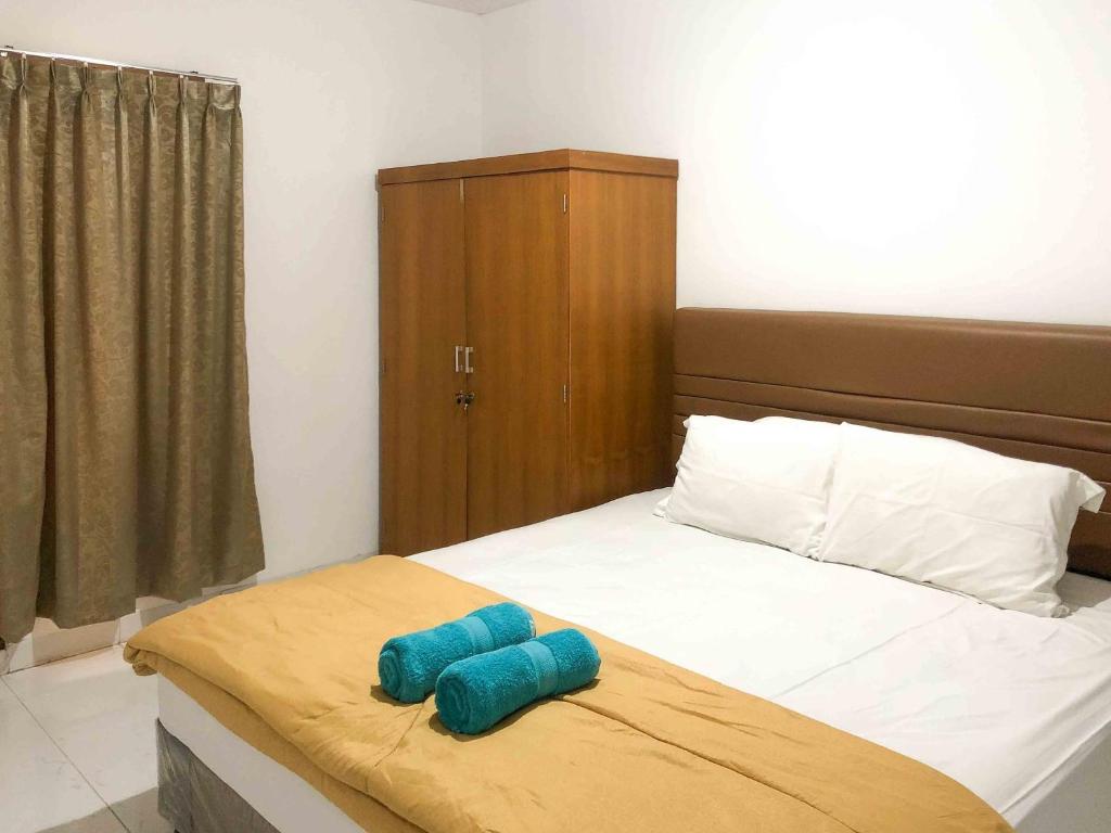 ein Bett mit zwei blauen Kissen darüber in der Unterkunft Sofia Residence Syariah Mitra RedDoorz in Malang