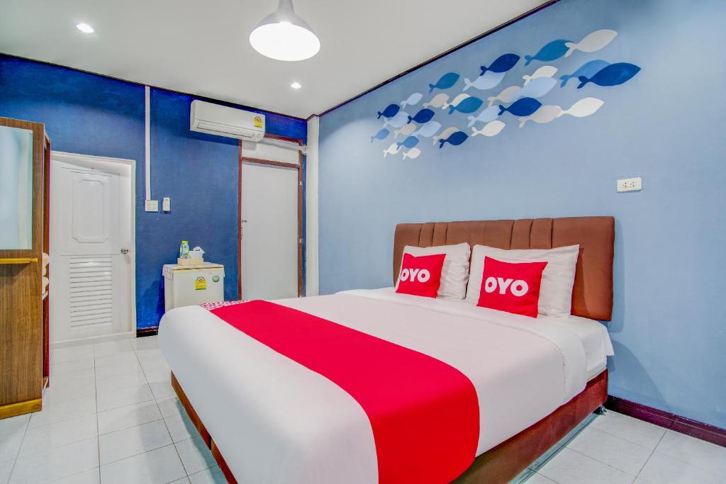 a bedroom with a large bed with two red pillows at OYO 428 Pha Mansion in Chachoengsao