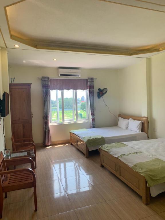 een slaapkamer met 2 bedden en een raam bij Nhà nghỉ Diễm Quỳnh Nội Bài in Hanoi