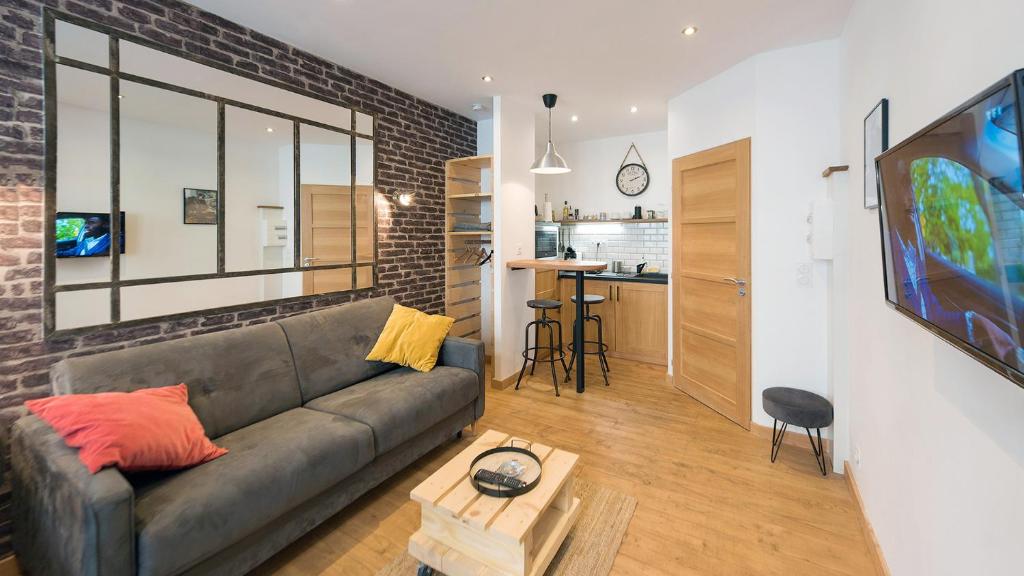 a living room with a gray couch and a kitchen at L'Atelier velours in Le Mans