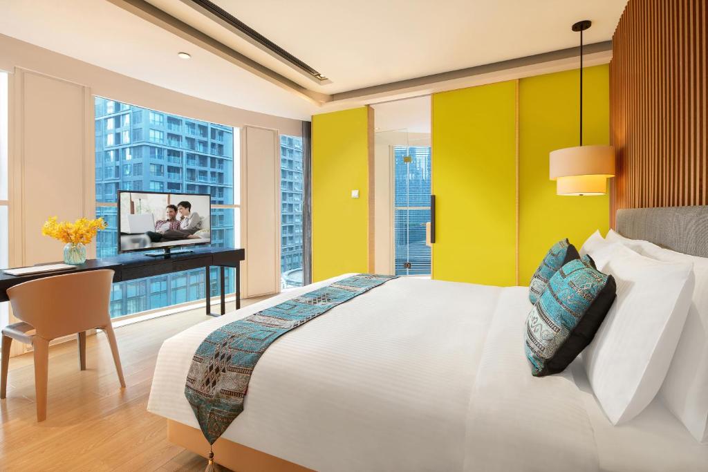 a bedroom with a large bed and a desk and windows at Citadines South Chengdu in Chengdu