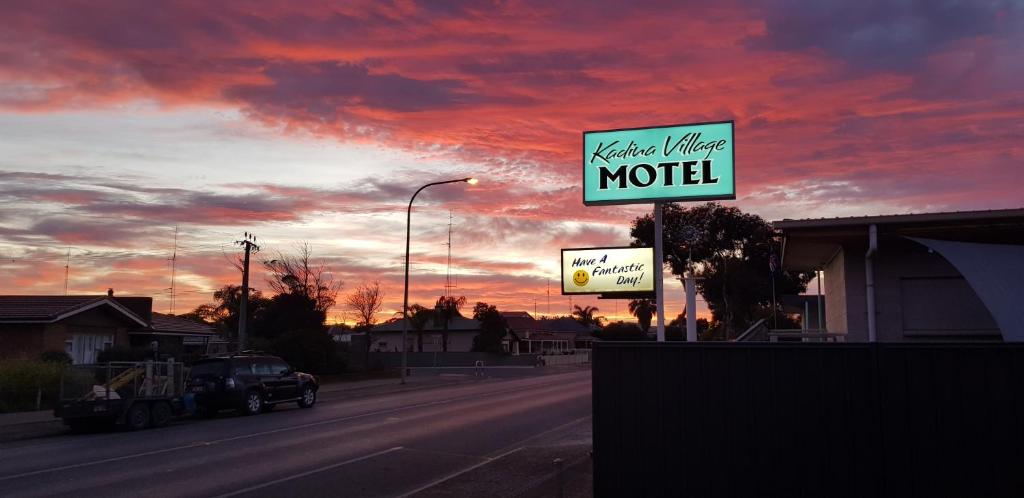 a motel sign on the side of a road with a sunset at Kadina Village Motel in Kadina