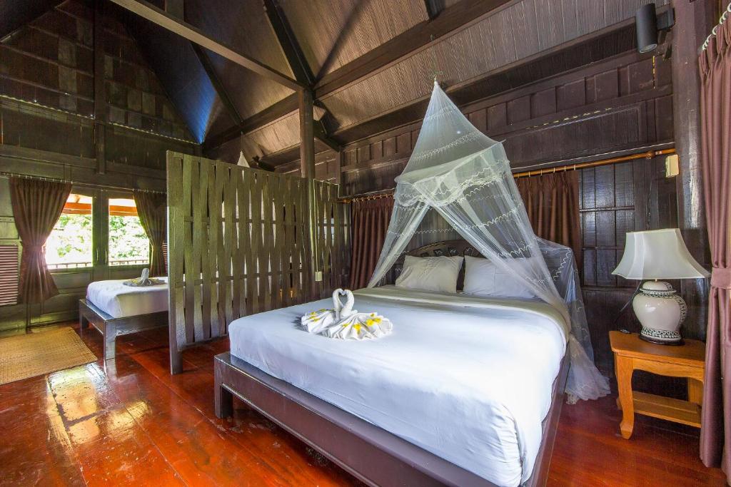 a bedroom with a bed with a net on it at Koh Talu Island Resort in Bang Saphan Noi