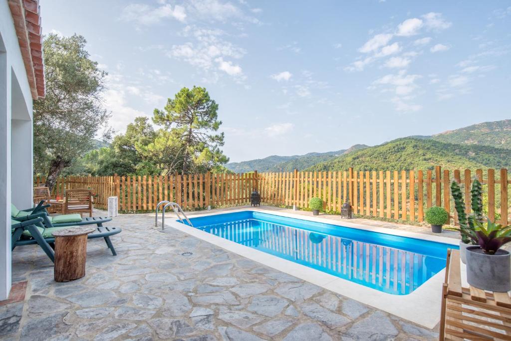 a swimming pool in a backyard with a wooden fence at Casa Rural Monte Dios in Jubrique