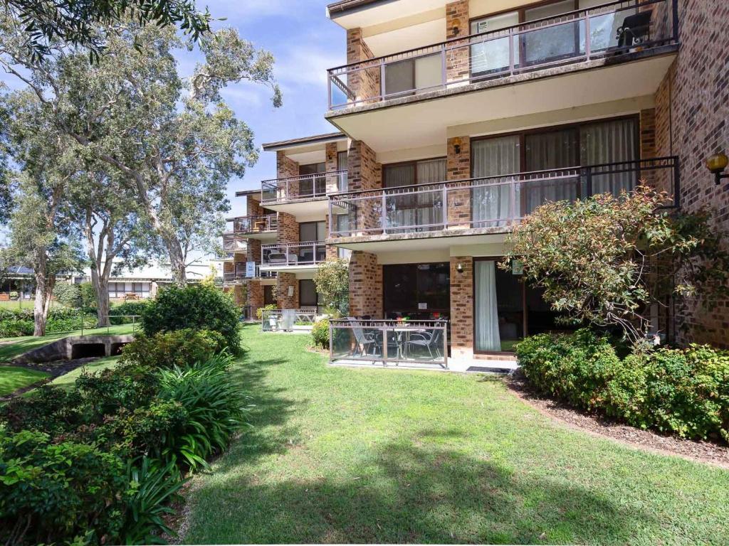 an apartment building with a lawn in front of it at Bay Parklands 57 ground floor unit with pool tennis court and aircon in Nelson Bay