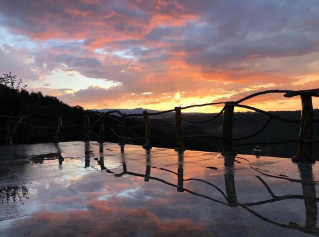 una puesta de sol sobre un cuerpo de agua con una valla en Hotel Villa Xtreme, en Villa del Carbón