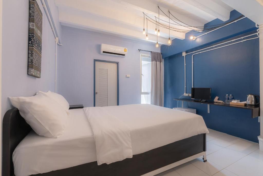 チェンマイにあるBEDGASM Hotel x Cafe Nimmanの青い壁のベッドルーム(白いベッド1台付)