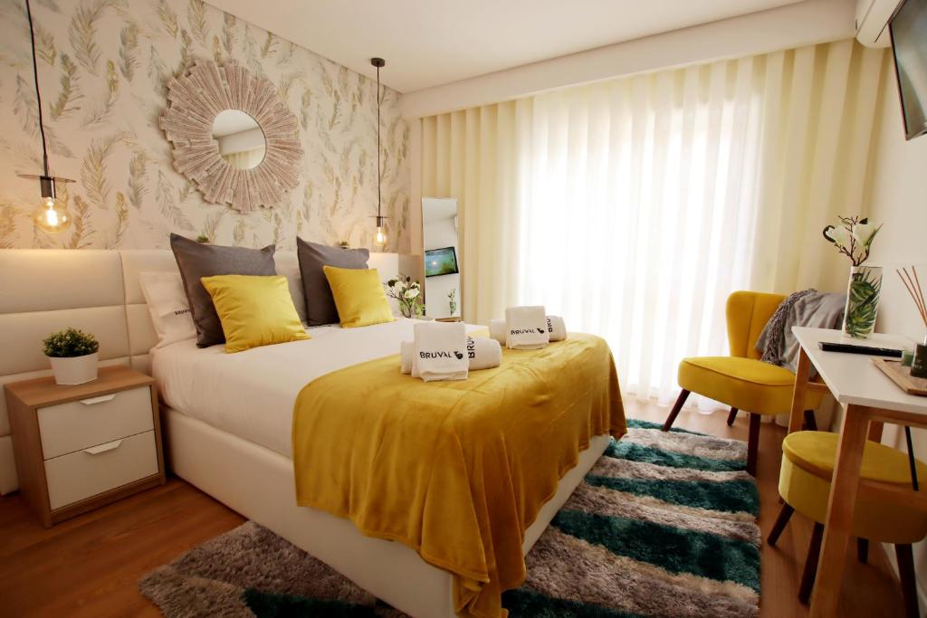 een slaapkamer met een groot bed met gele lakens en een bureau bij Bruval Premium Apartments - Gaia in Vila Nova de Gaia