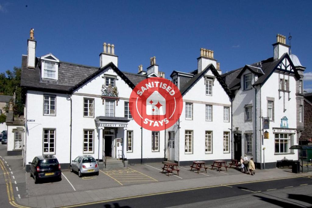 Um edifício branco com um sinal vermelho à frente. em Burnett Arms Hotel em Banchory