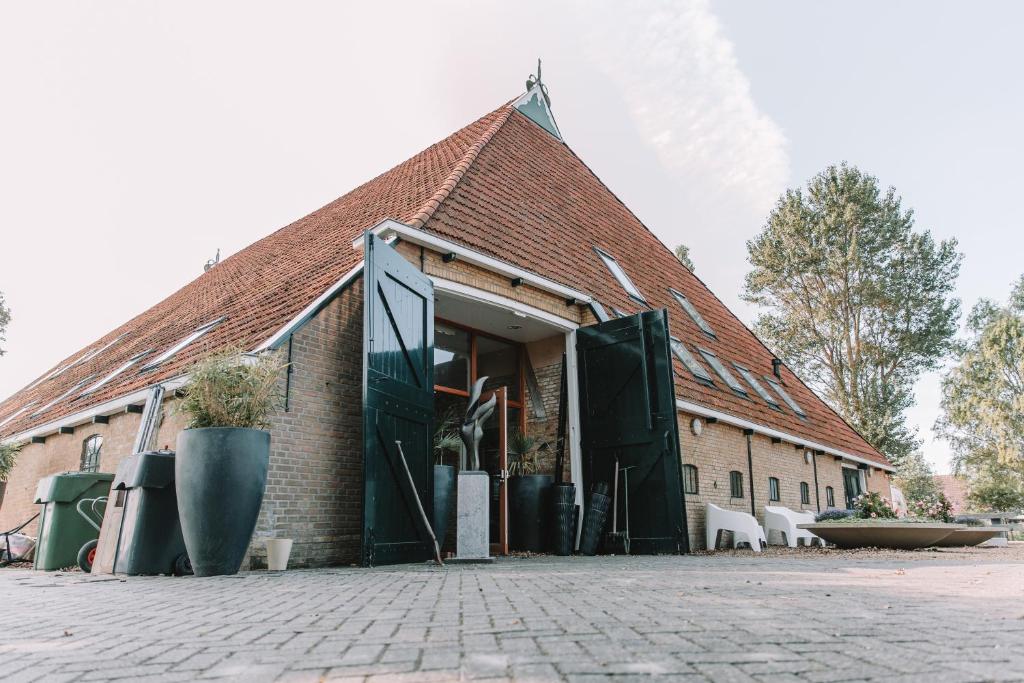 ハルリンゲンにあるHarlingen Staete Wellness B&B Oase van rust en luxeのレンガ造りの建物に開くドア付きの建物