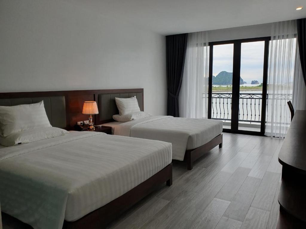 Una habitación de hotel con dos camas y balcón. en Ha Long Bay TC Hotel, en Ha Long