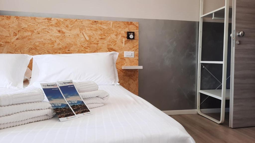 a white bed with towels and a book on it at Bergamo GuestHouse - Self Check-in in Curno