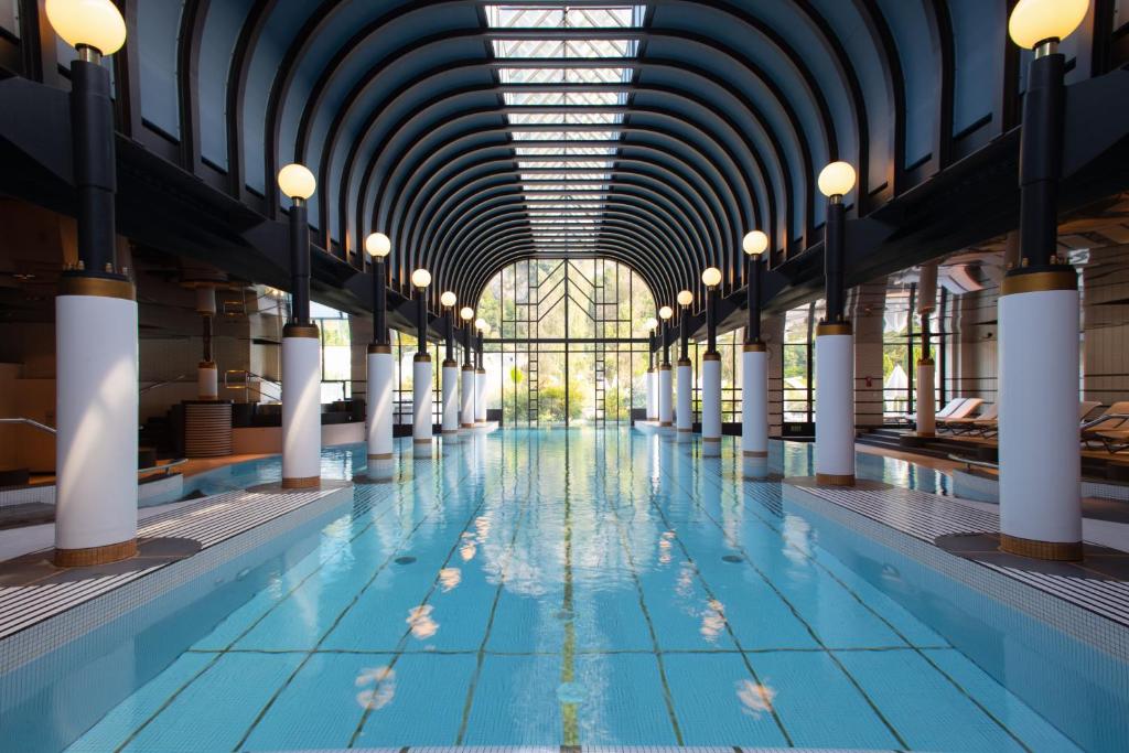 an indoor swimming pool with a ceiling and lights at Victoria Jungfrau Grand Hotel & Spa in Interlaken