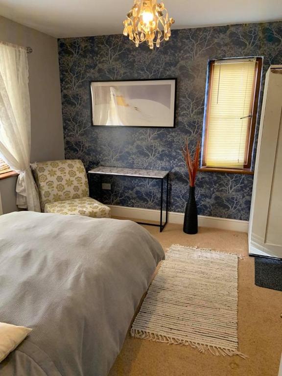 a bedroom with a bed and a chair and a table at Riverside B&B in Kidwelly