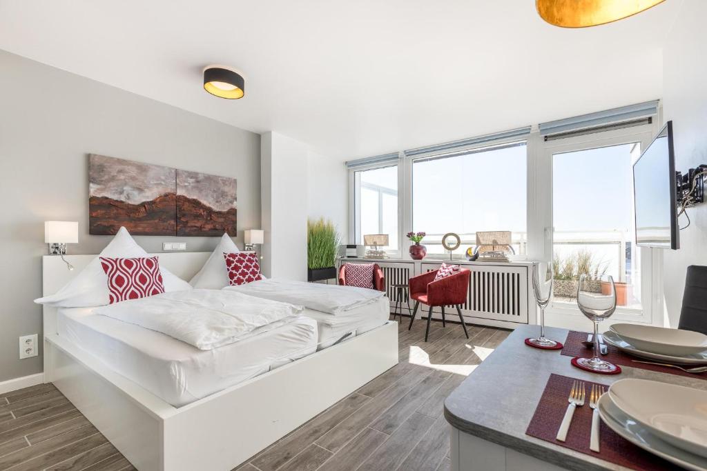 ein weißes Schlafzimmer mit einem Bett und einem Esszimmer in der Unterkunft Ferienwohnung Penthouse in Westerland