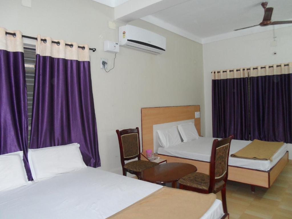 a room with two beds and a table and chairs at Hotel Pasuparthy Residency in Tirupati