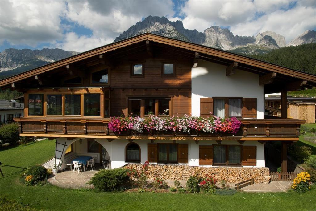 une grande maison en bois avec des fleurs sur le balcon dans l'établissement Haus Alexander, à Ellmau