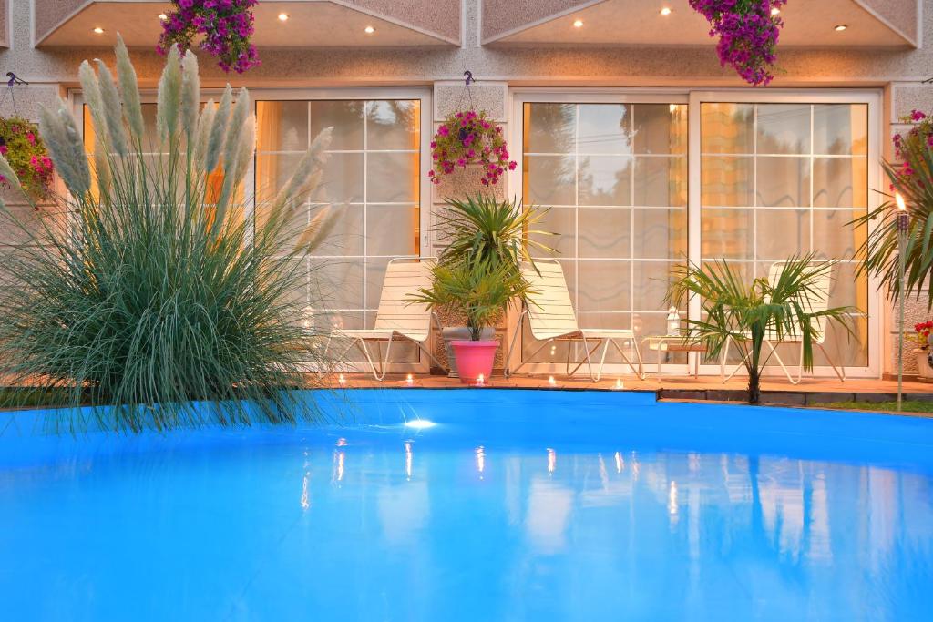 a blue swimming pool in a house with plants at Aloha Luxury Apartments in Skopje