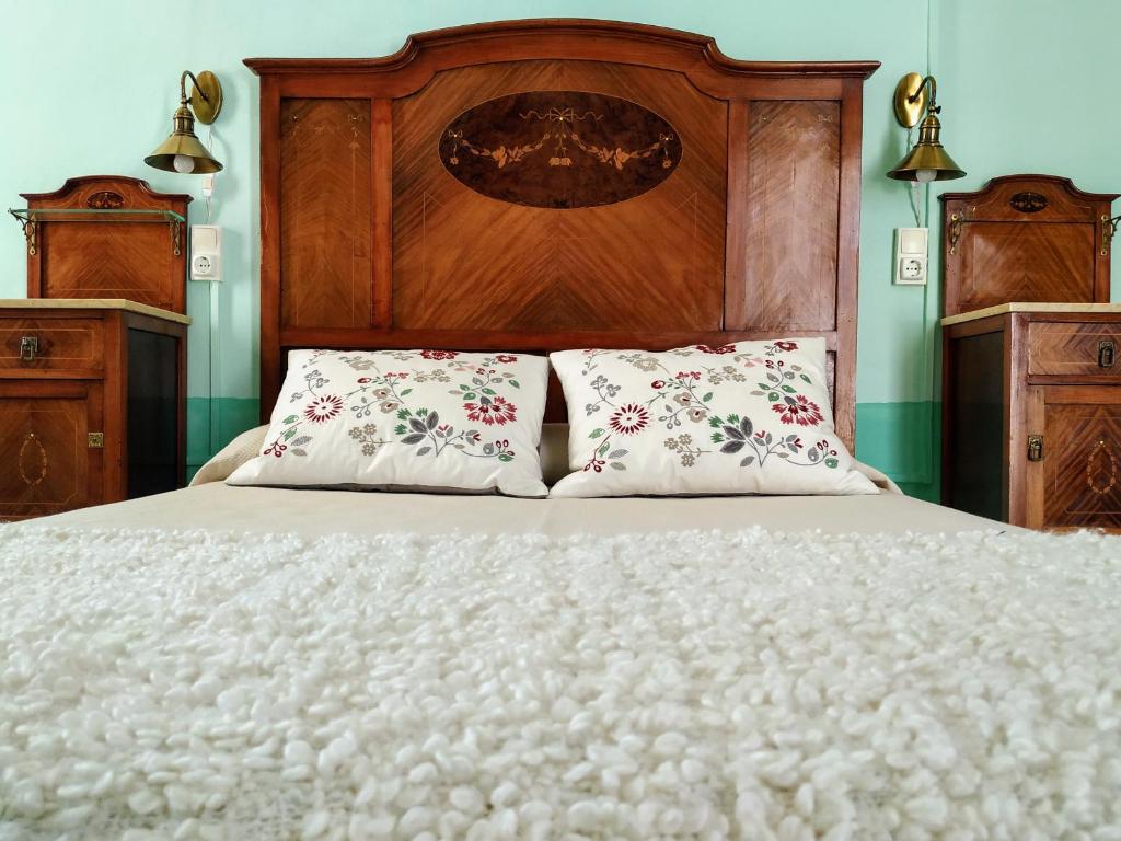 a bed with a wooden headboard and two pillows at Ca Les Senyoretes in Otos