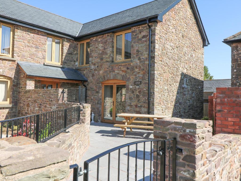 a brick house with a bench in front of it at Grange Cottage in Crediton