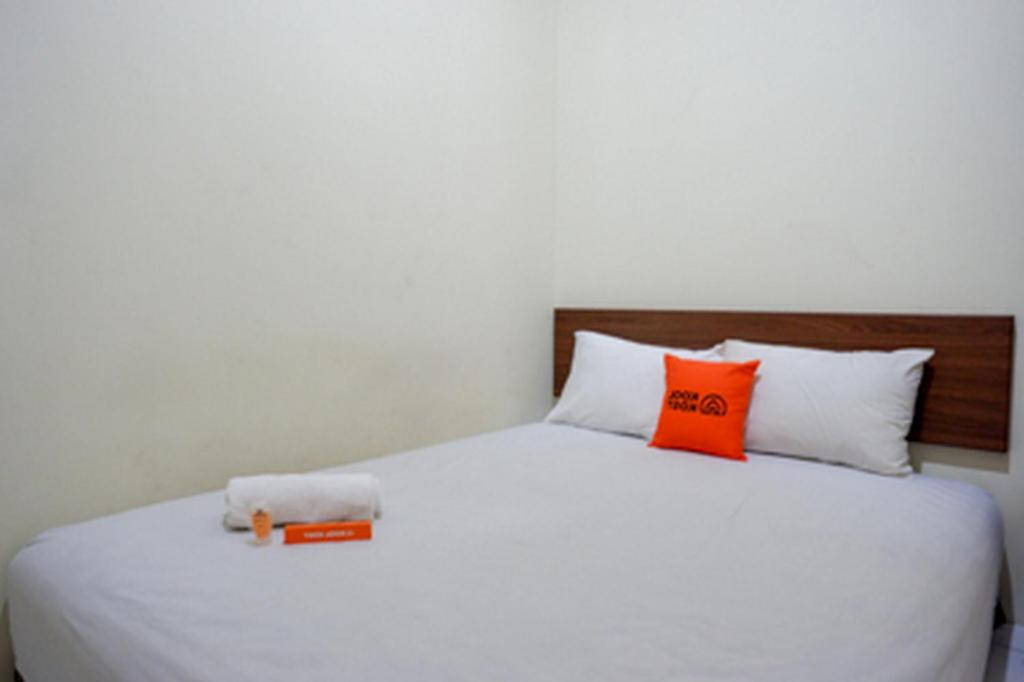 Una cama con almohadas de color naranja y blanco. en KoolKost at Jl Unta Pandeyan Lamper Semarang - Minimum Stay 30 night, en Semarang