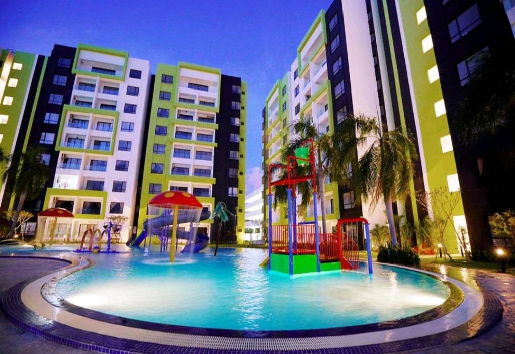 イポーにあるHOMESTAY COMFY CONDO with Waterpark, Pool, Playground & Gymの一部の建物の前に遊び場付きの大型プールがあります。