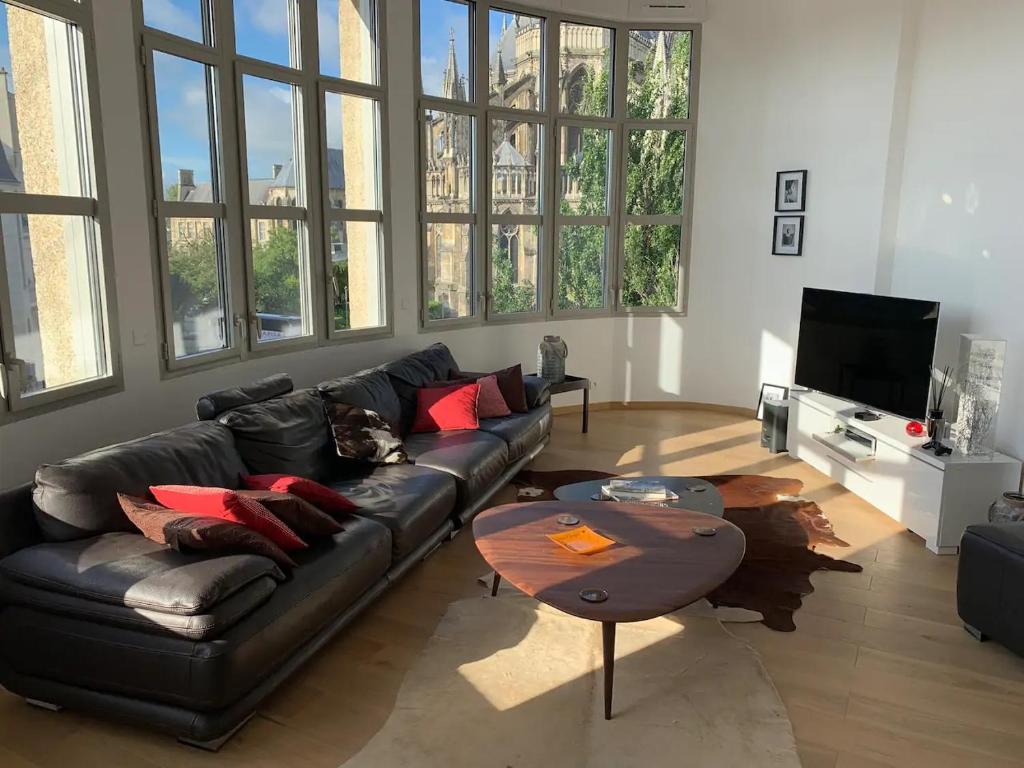 a living room with a leather couch and a table at Loft des Sacres - Vue unique sur la Cathédrale in Reims