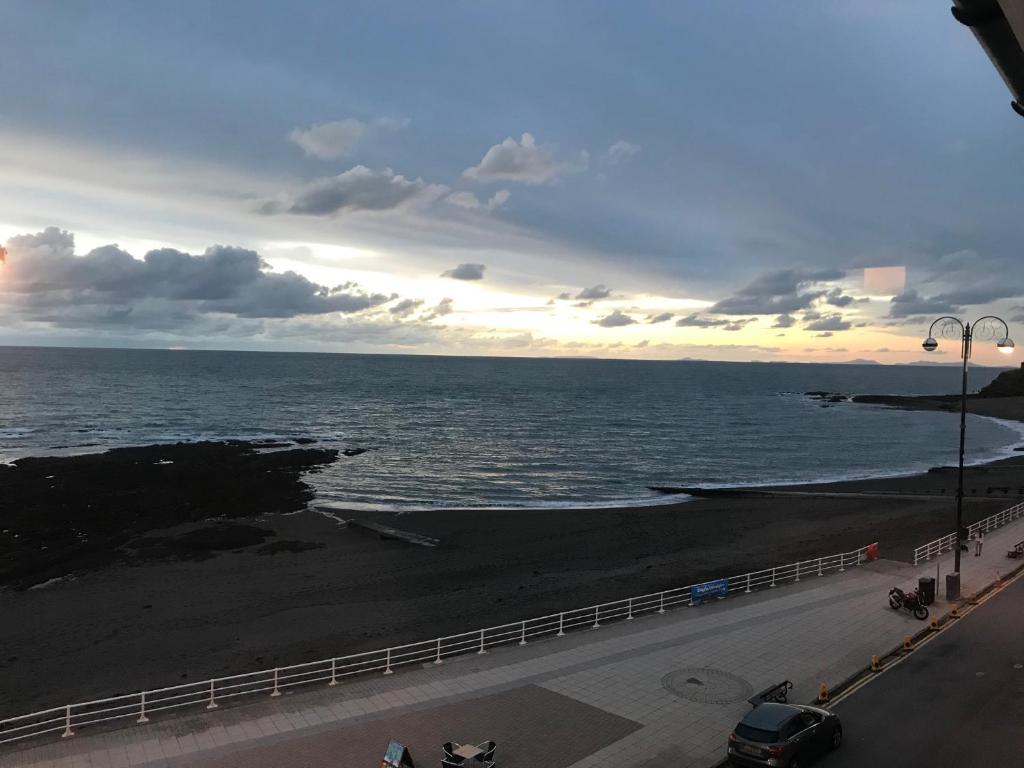 a view of a beach with a fence and the ocean at Belmont - Y Prom in Aberystwyth