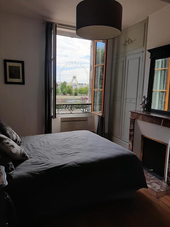 um quarto com uma cama e uma janela com uma roda gigante em Et au pied coule une rivière, situation et vue idéales em Auxerre