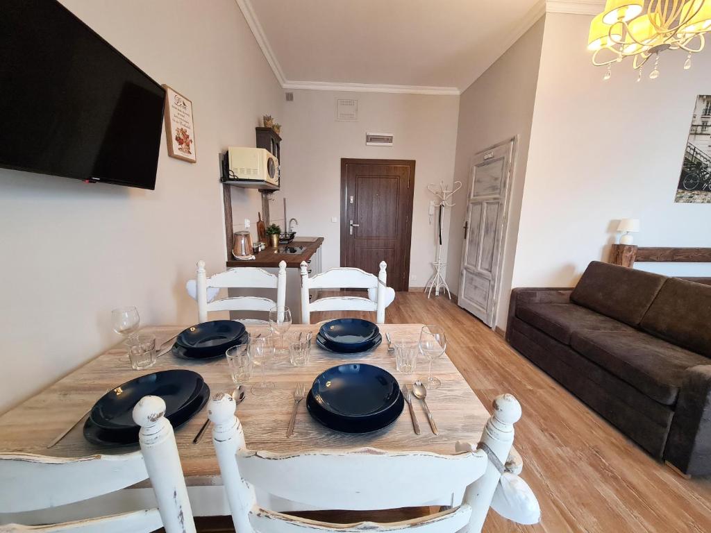 mesa de comedor con sillas blancas y sofá en Apartament Starówka 6 en Toruń