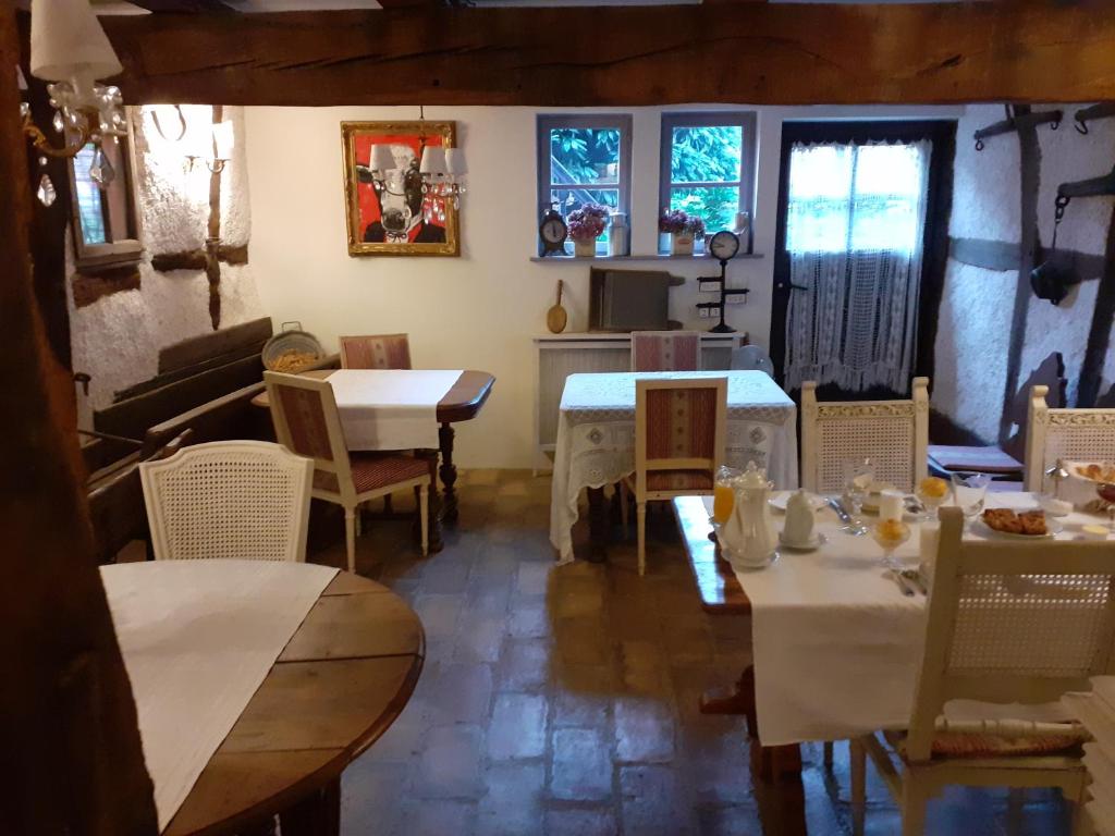 a dining room with tables and chairs and windows at Aux temps d'avant in Gundershoffen
