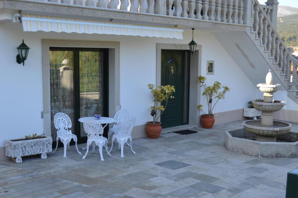 un patio con una mesa, sillas y una fuente. en Casa Concha, en Porto do Son