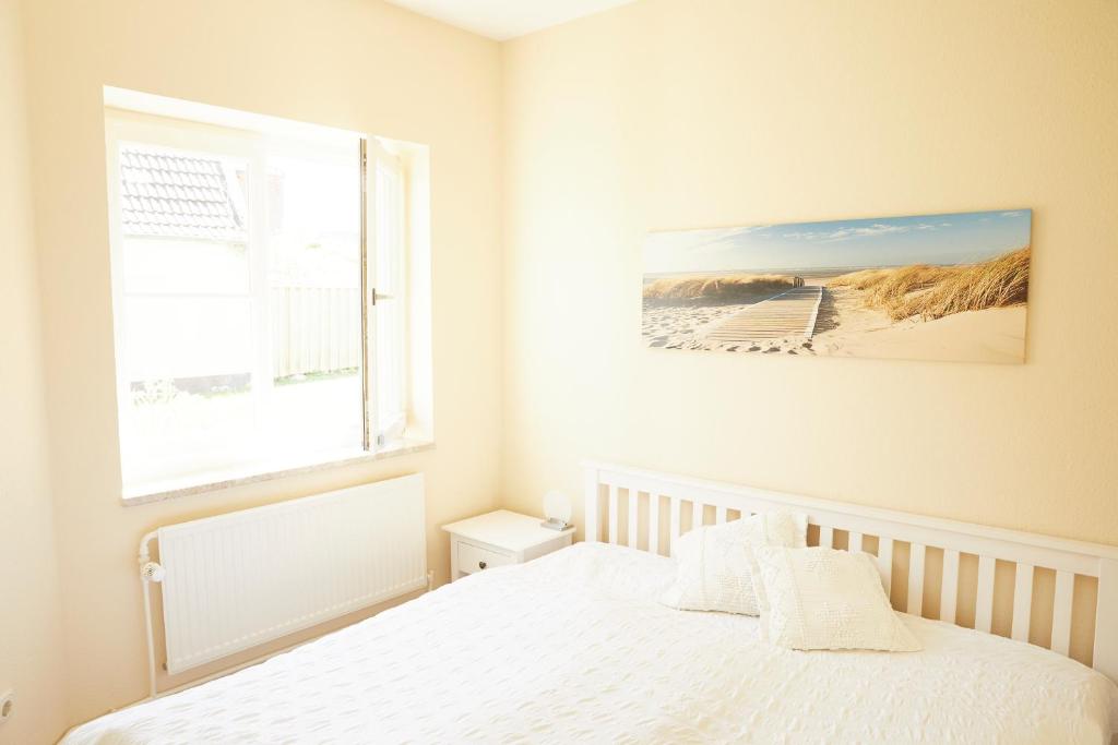 ein weißes Schlafzimmer mit einem Bett und einem Fenster in der Unterkunft Ferienwohnungen Zum Goldenen Anker in Tönning