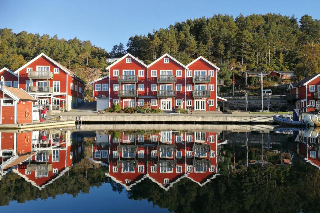 a group of red houses next to a body of water at Tregde Ferie in Mandal